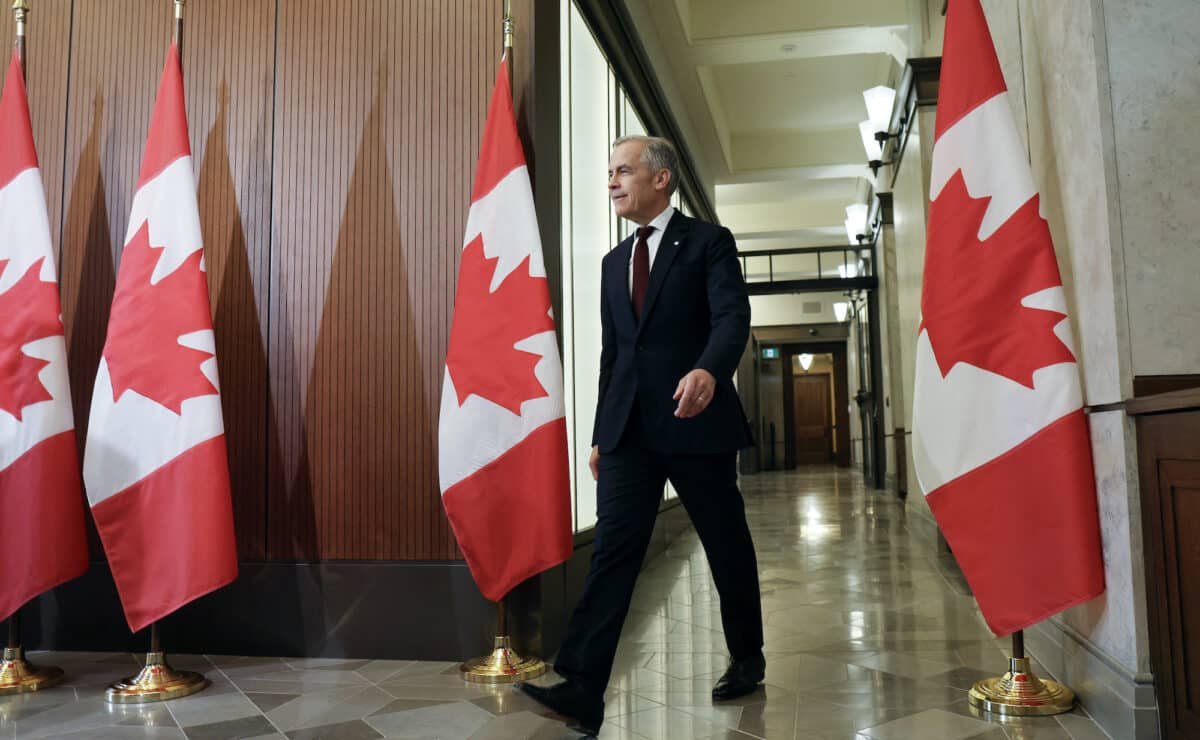 Canadian Prime Minister Mark Carney walks past Canadian flags
